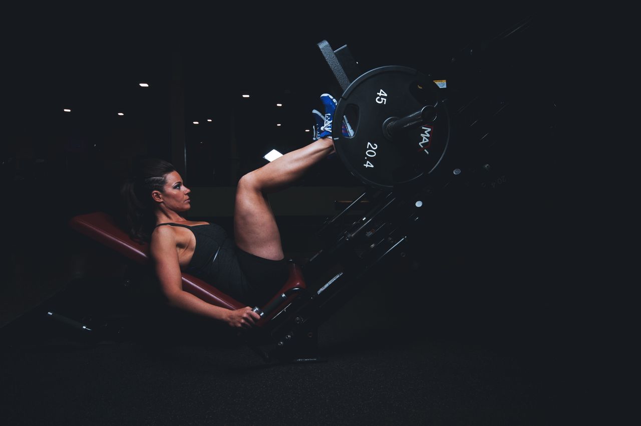 hero-img-02 A woman engages in an intense leg press workout at the gym, showcasing strength and fitness.