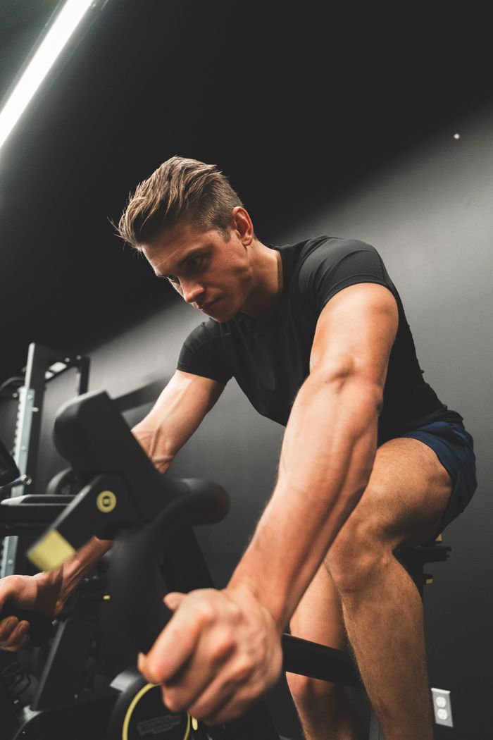 services-02 Fit young man intensely cycling on a stationary bike indoors.